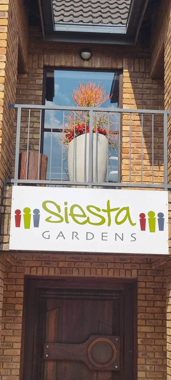 The Siesta Gardens sign on the balcony above the front door